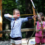 Kid shooting archery at summer camp