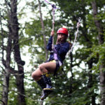 Teen girl riding camp zip line