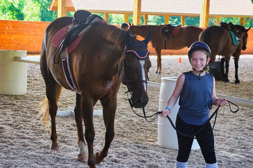 girl camper walking with horse