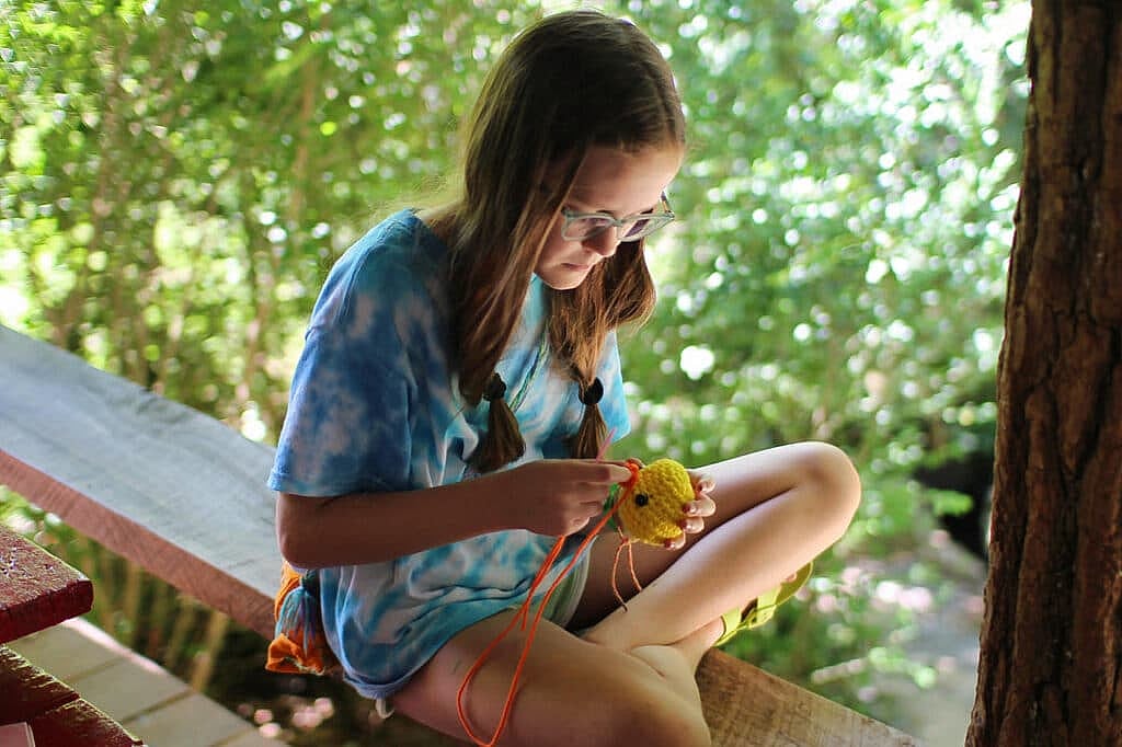 girls camper making crochet creature