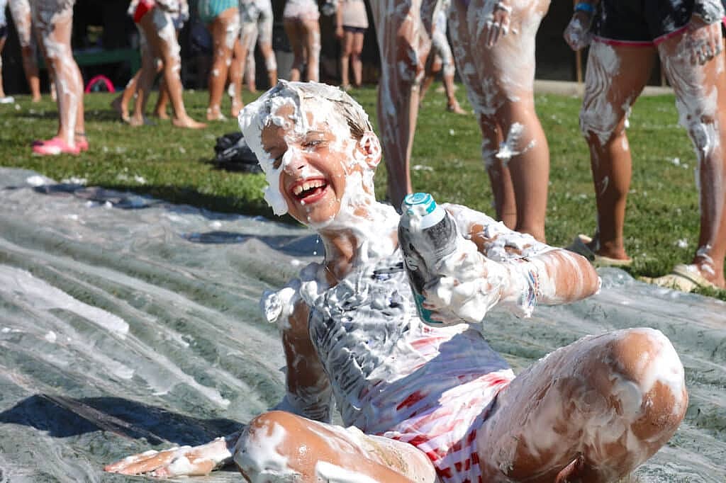 summer camp girls laughing on shaving cream slide