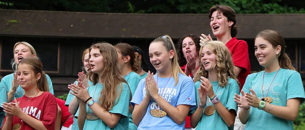 teenage camp girls clapping at assembly