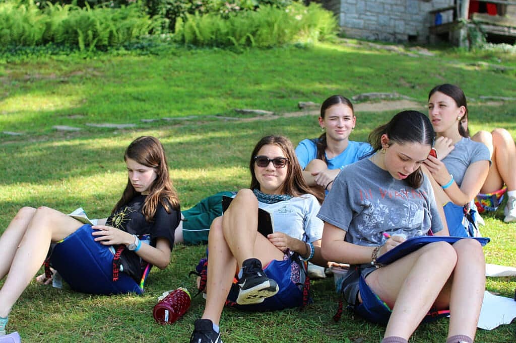 teenage campers reading club on hill