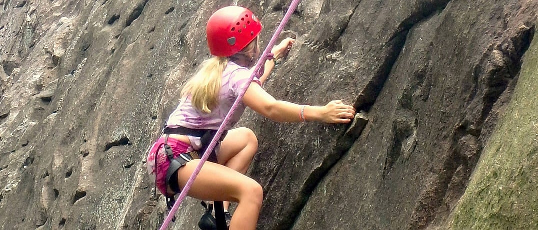 camp girl making climbing move