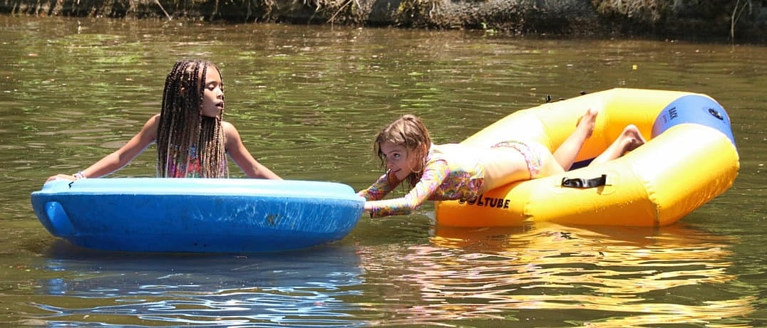 two kids playing in lake floats