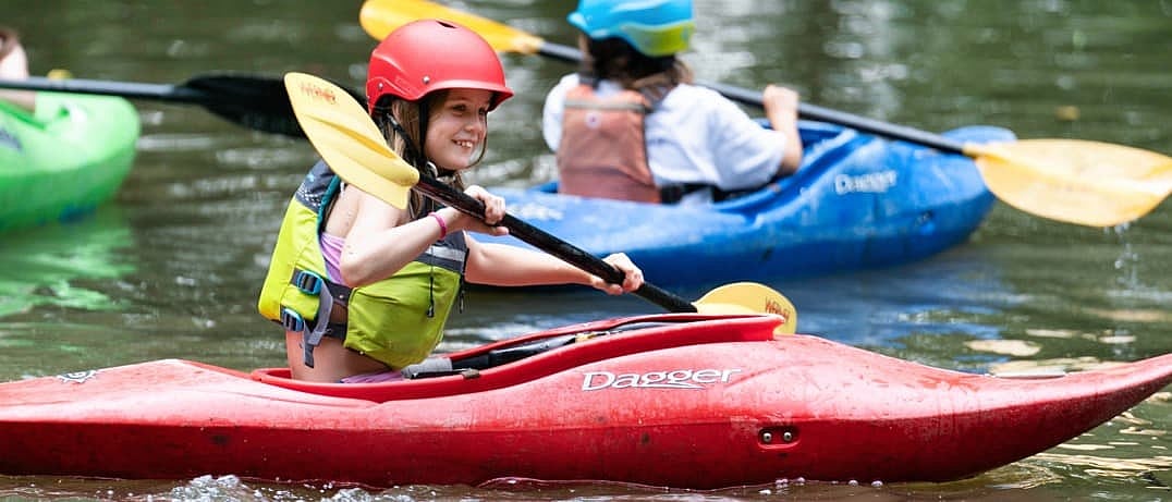 small girl kayaking at camp