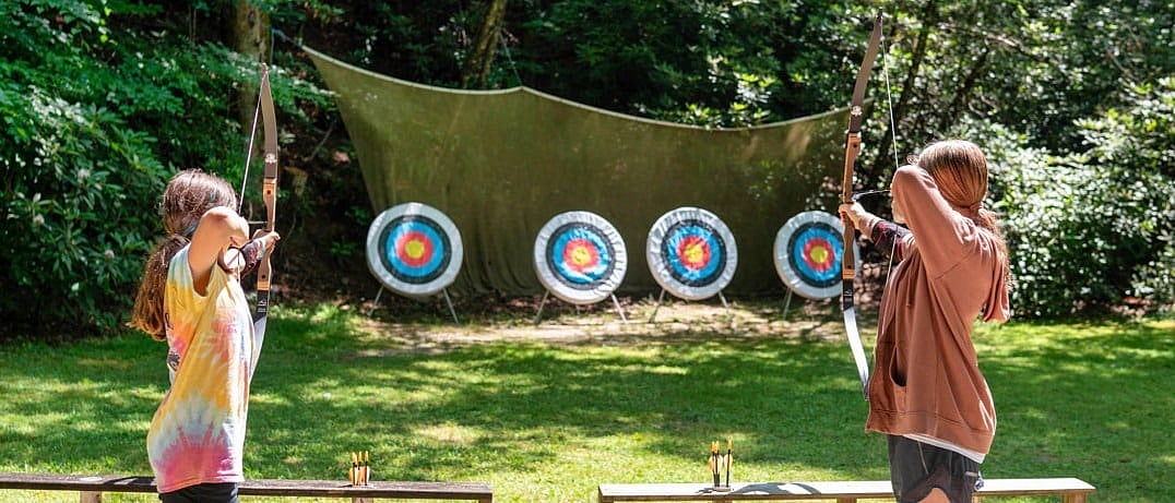 girls camp archery aiming at targets