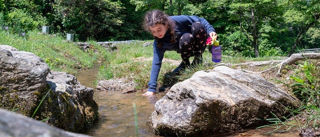 camp girl exploring creek
