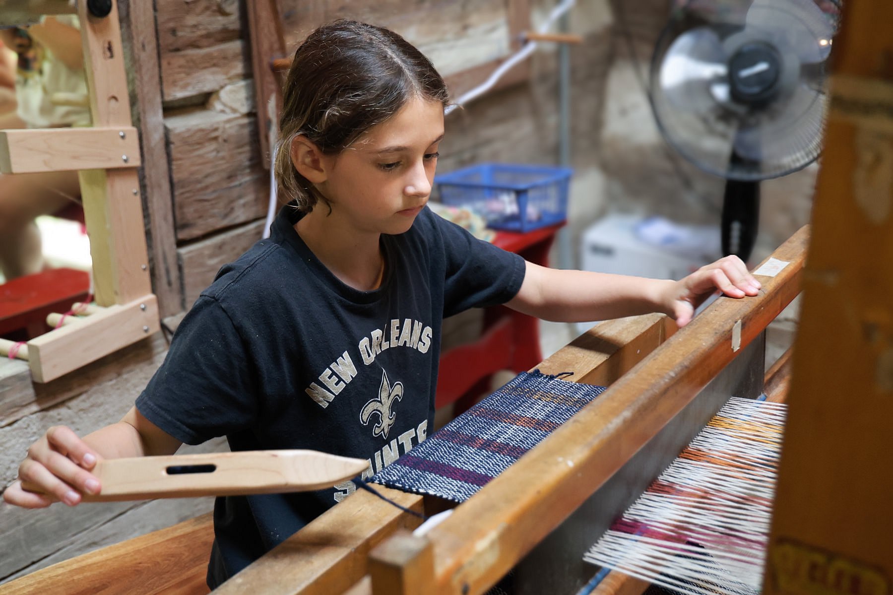 young girl weaving on loom