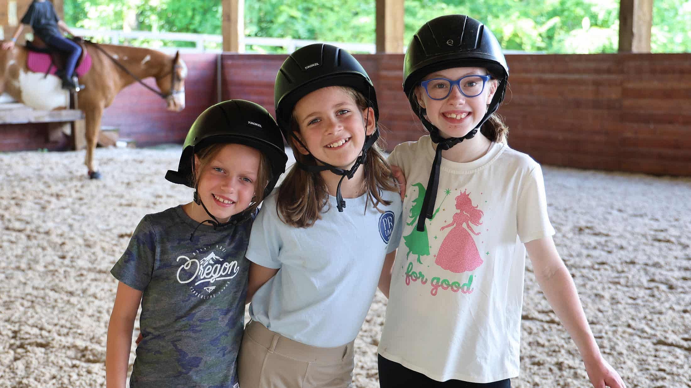 three camp horse girls wearing helmets