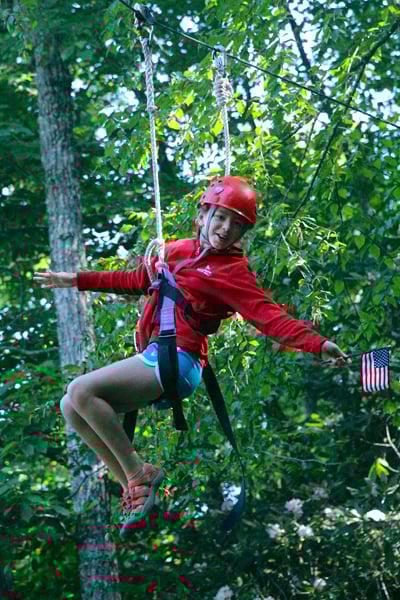 Camp holding USA flag on zipline