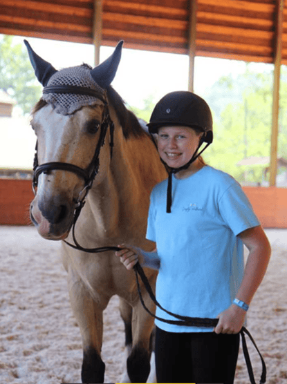 buckskin horse and girl wearing helmet and blue shirt