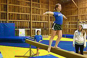 Camp child doing gymnastics on balance beam