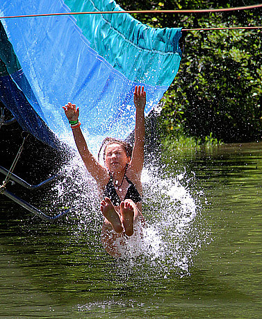 Girls splashing into lake from water slide