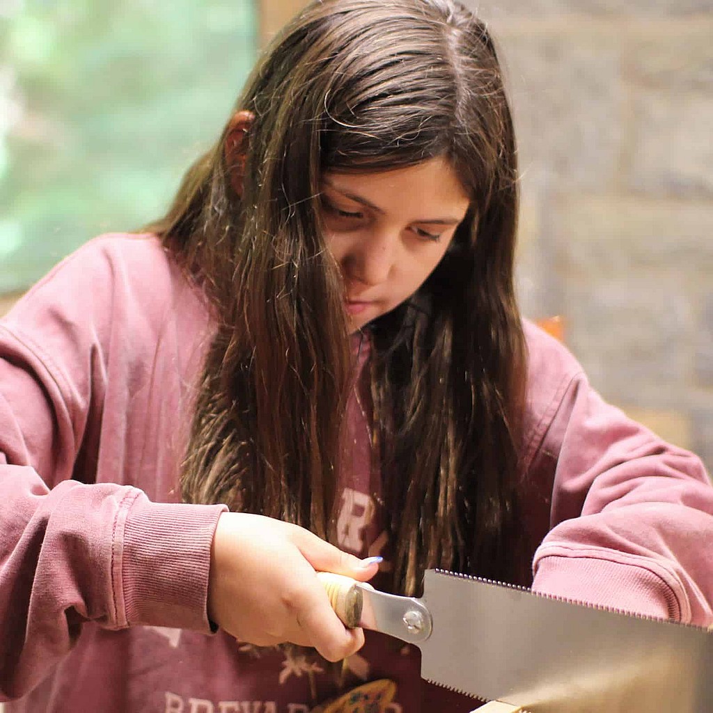 summer camp girl sawing wood