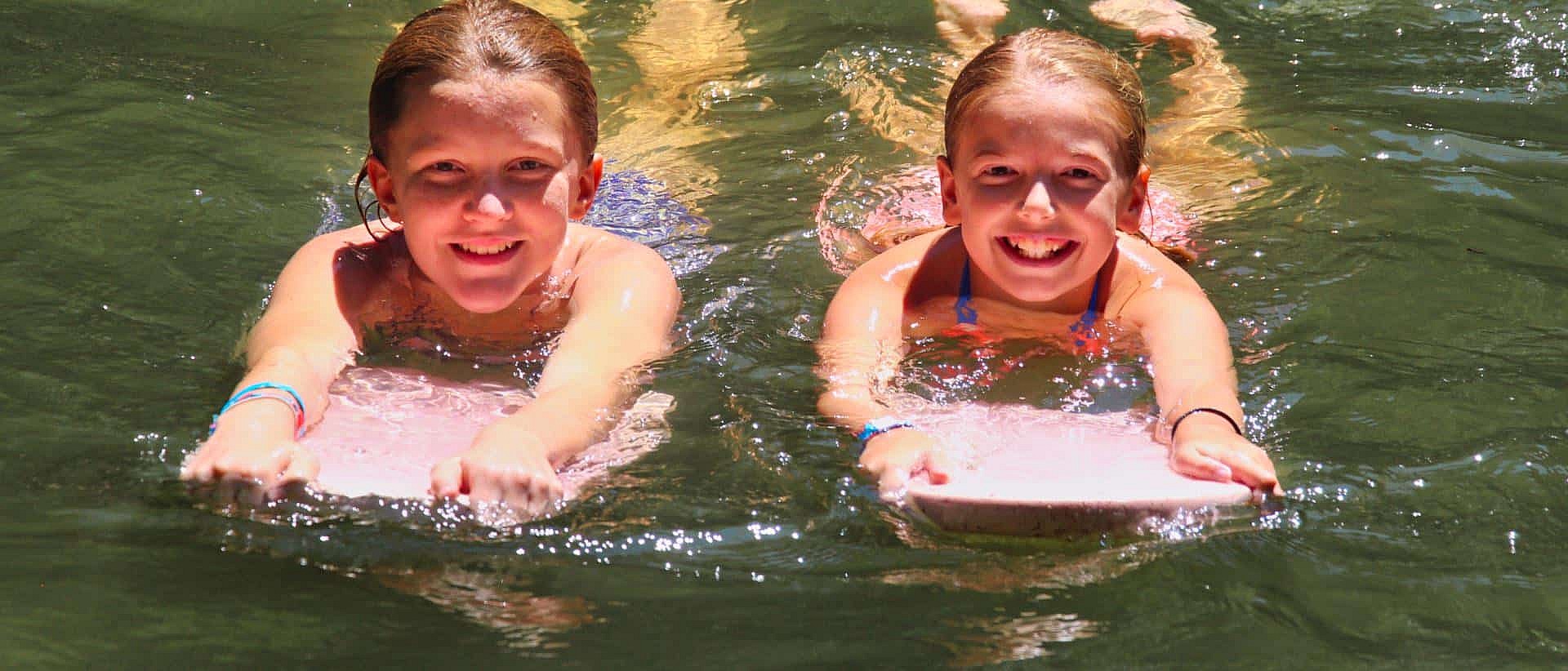 camp girls swimming with kick boards