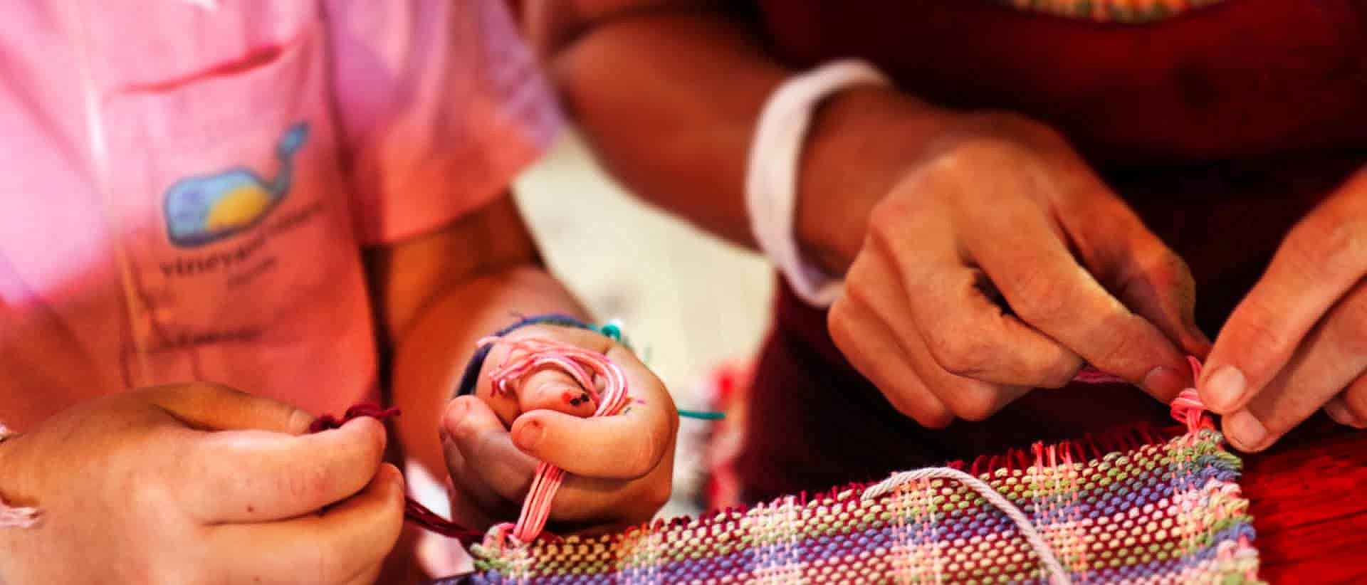 staff helping girl tie weaving