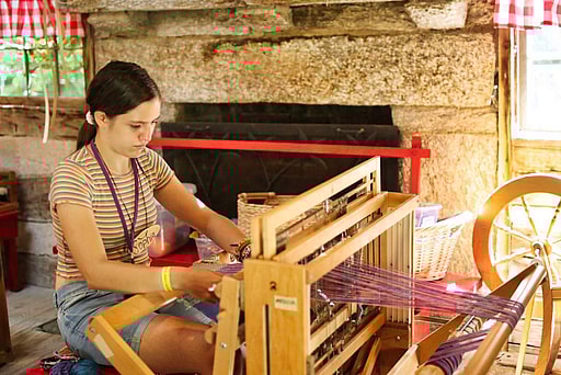 camp girl weaving on floor loom