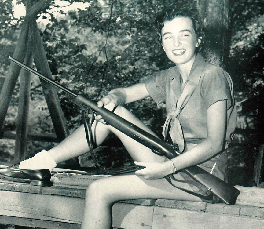 girl posing with rifle at camp