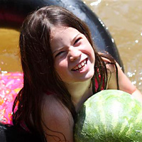 camp girl swimming with a watermelon