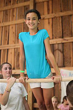 Camp girl balancing on gymnastics high bar