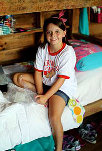 Girl sitting on her camp bunk bed