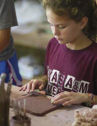 Girl works on clay slab in camp ceramics class