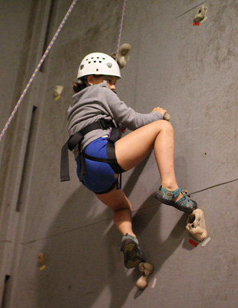 Rock climbing girl on wall in gym