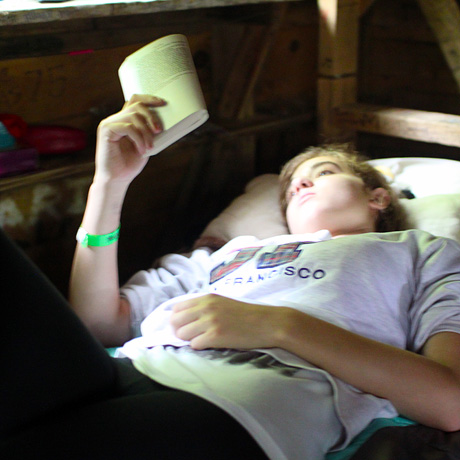 Girl reading book during rest hour at summer camp