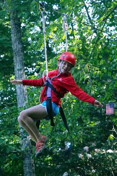 Camp holding USA flag on zipline