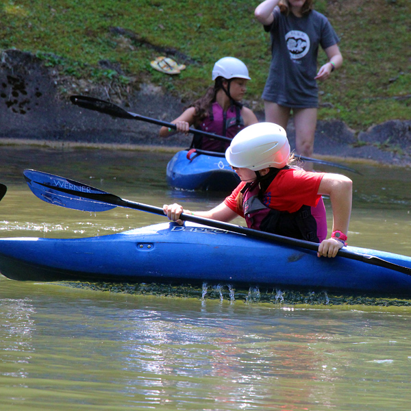 Girls learning to roll a kayak at the lake