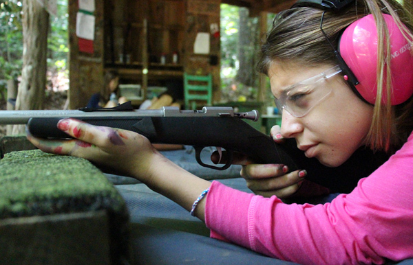 camp girl aiming a rifle