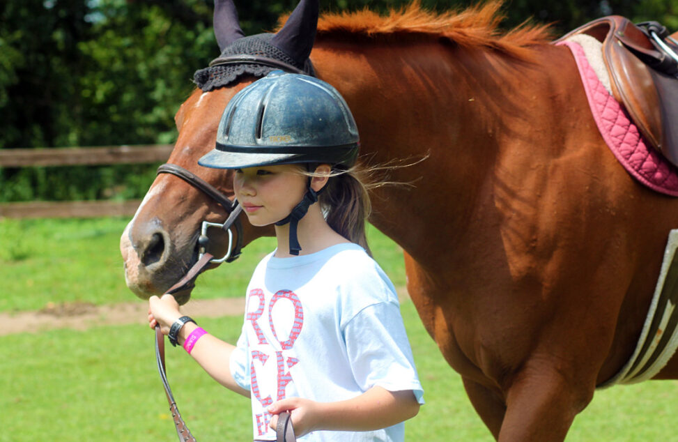 girl leading horse at camp