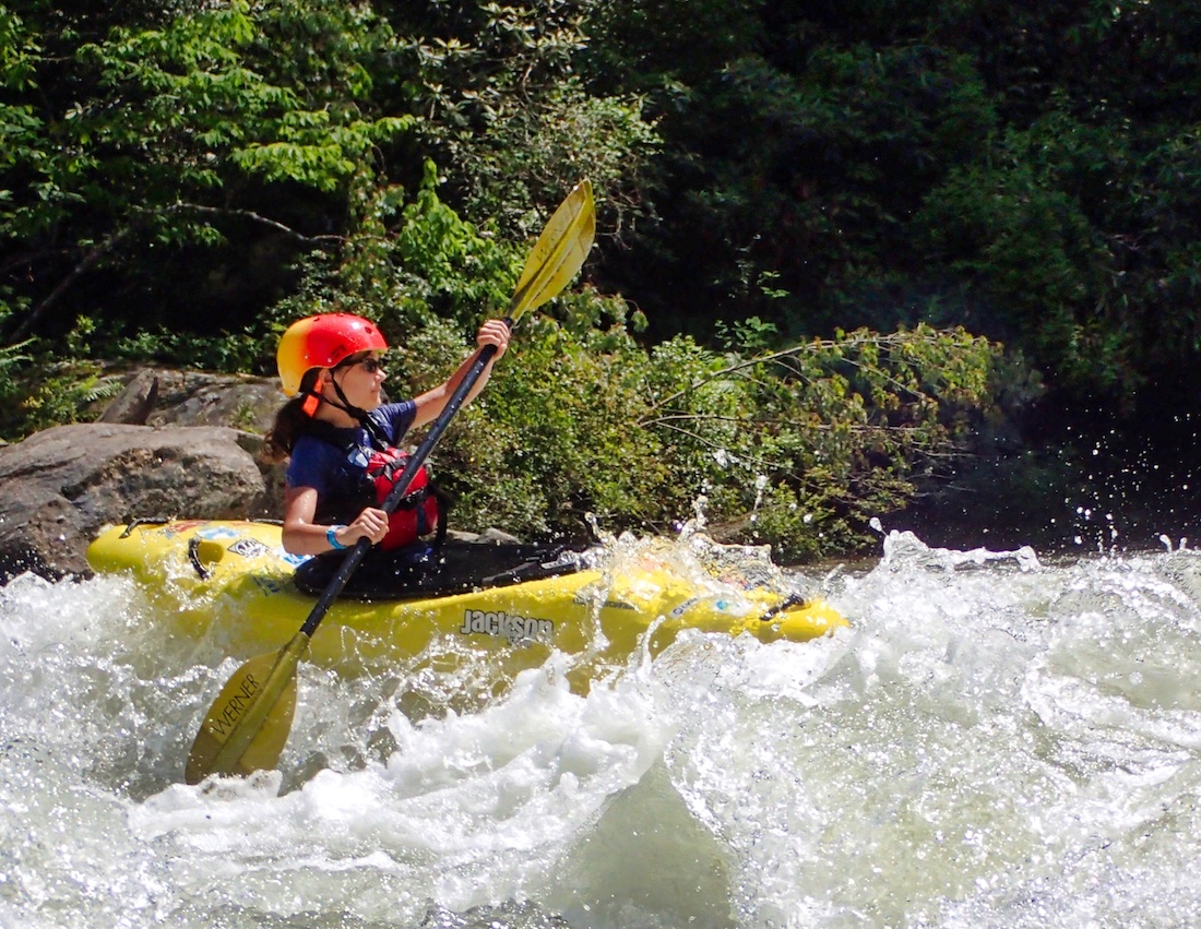 small camp girl kayaking in rapid