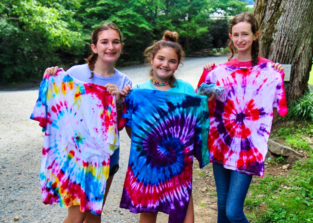 girls holding up tie-dye t-shirts they made