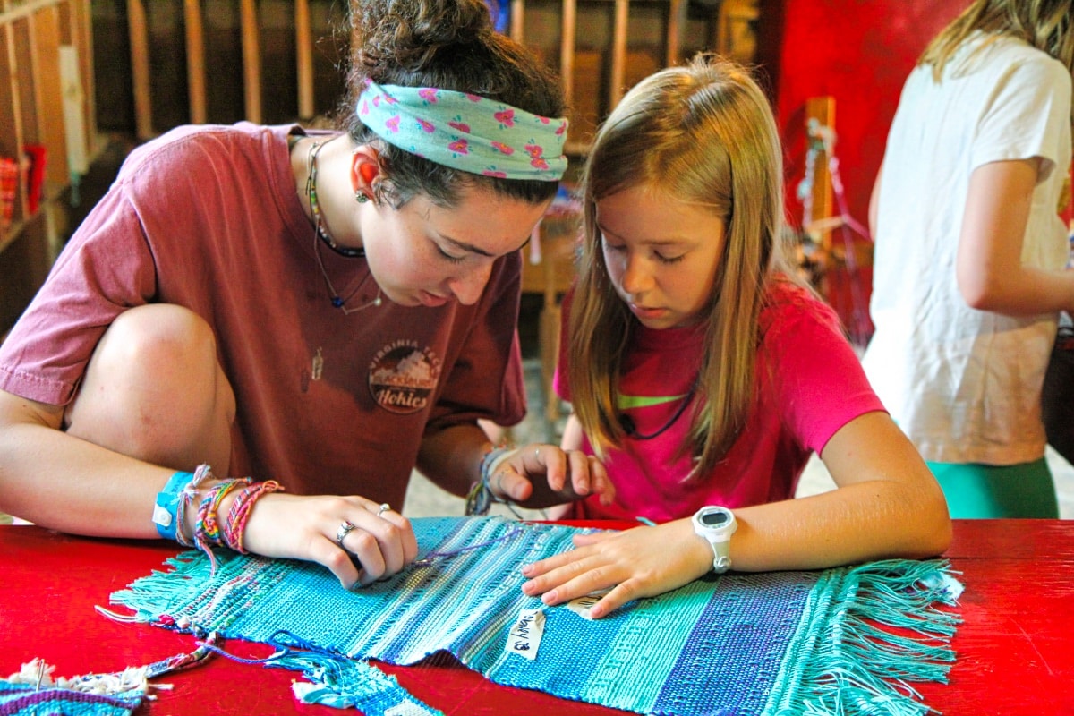 counselor and camper working on weaving