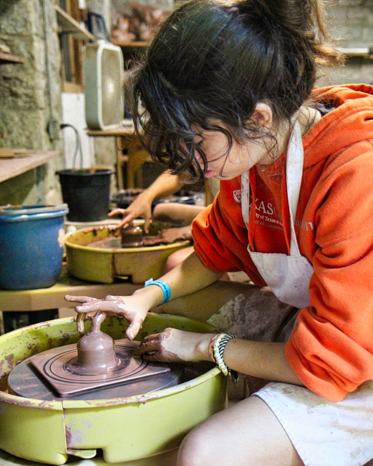 kid throwing on the potter's wheel 