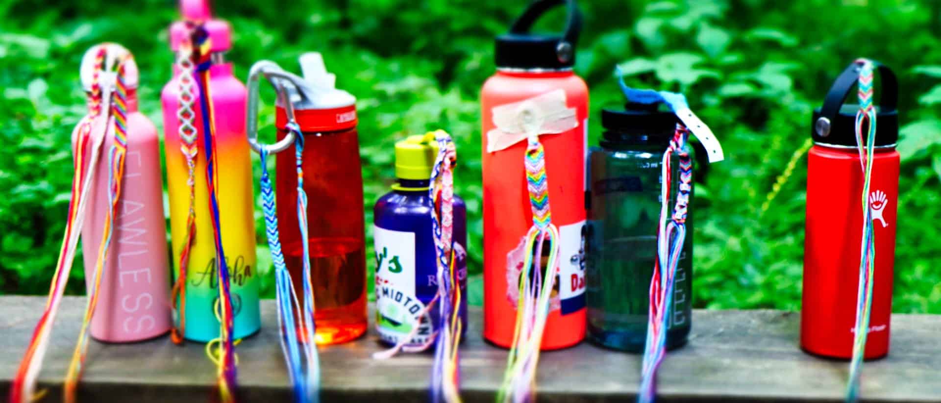 row of camp water bottles with friendship bracelets tied on