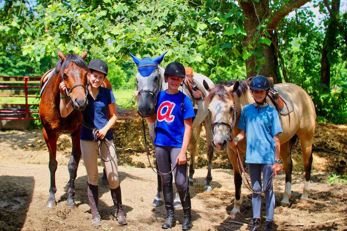 Horse camp girls wearing riding helmets