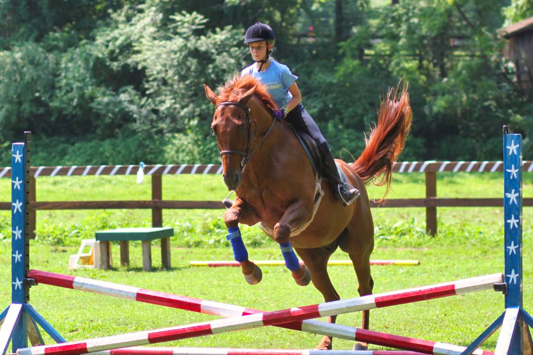 girl jumping a horse at summer camp