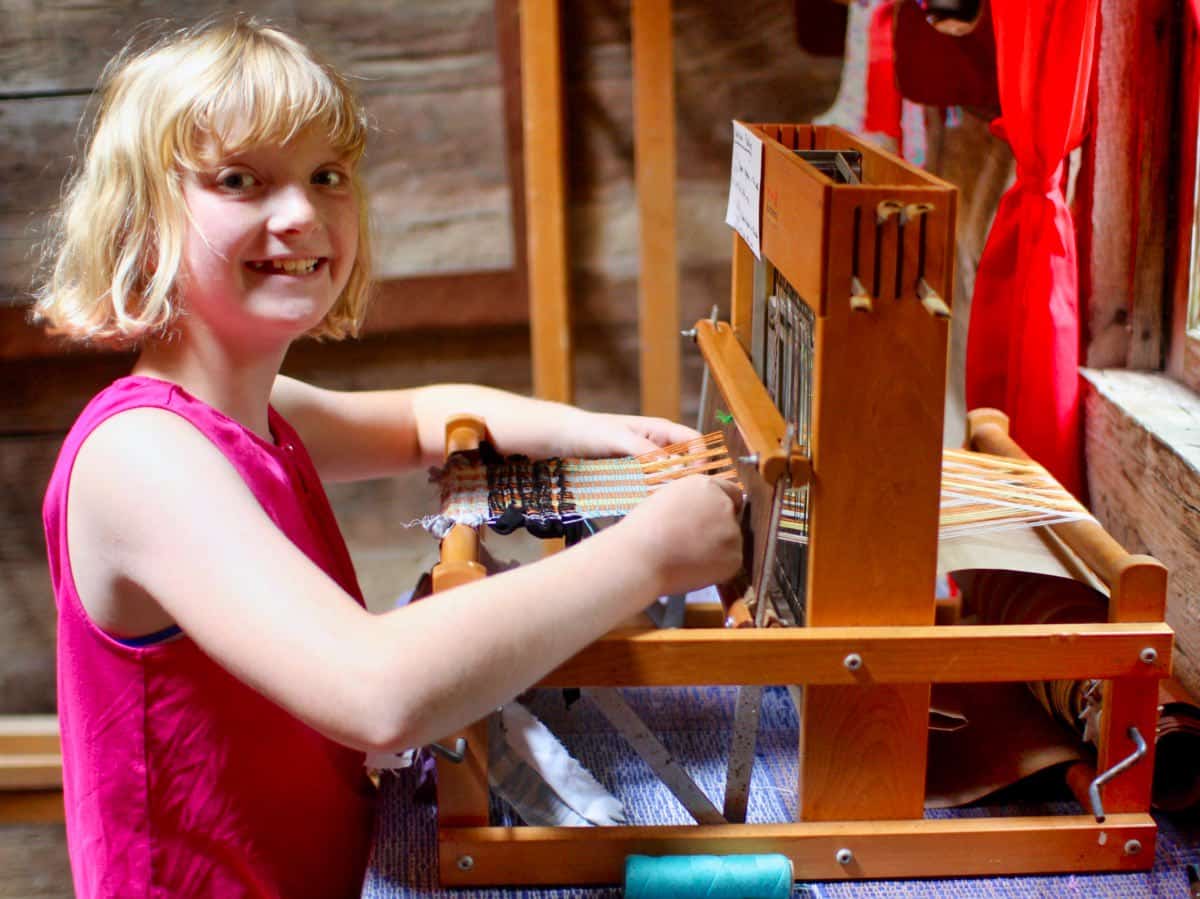 girls camp weaving crafts on a loom