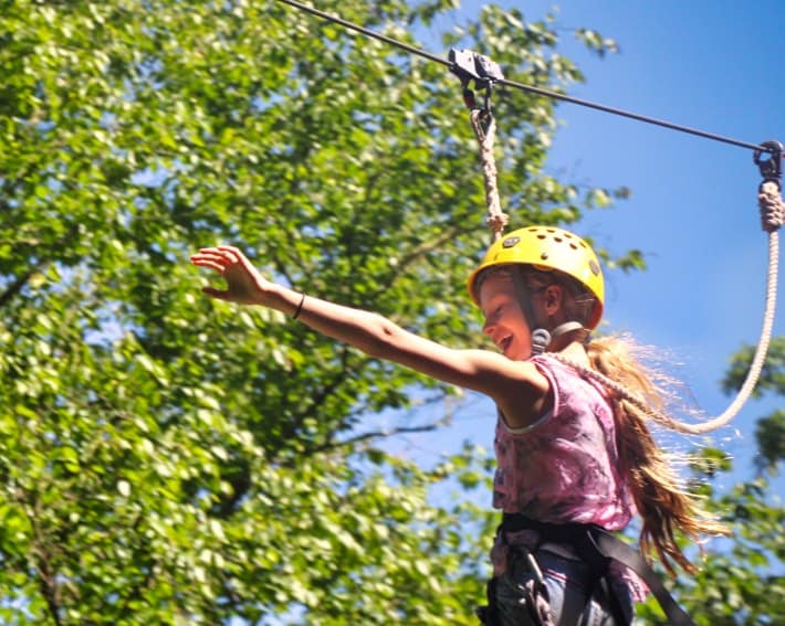 camp girl zip lining outdoors in the trees