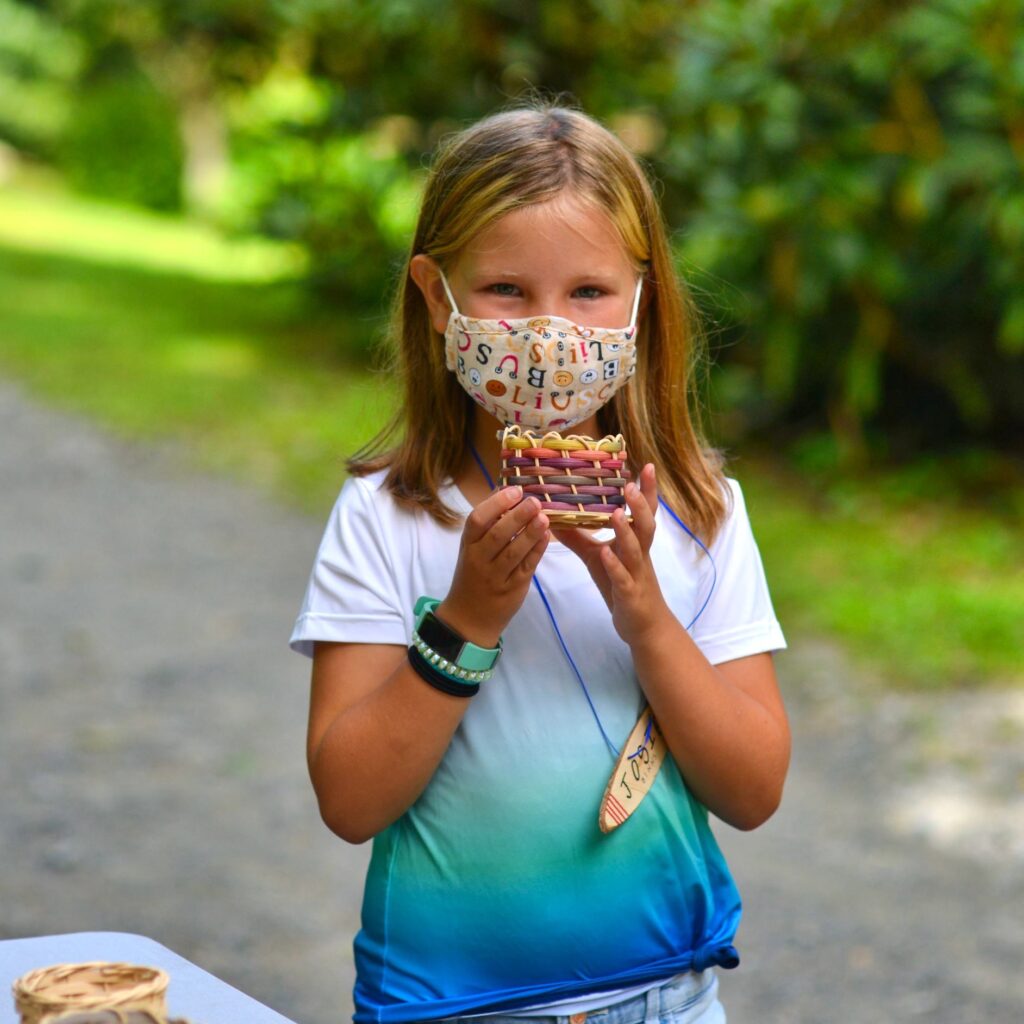 camp girl holding a basket she made