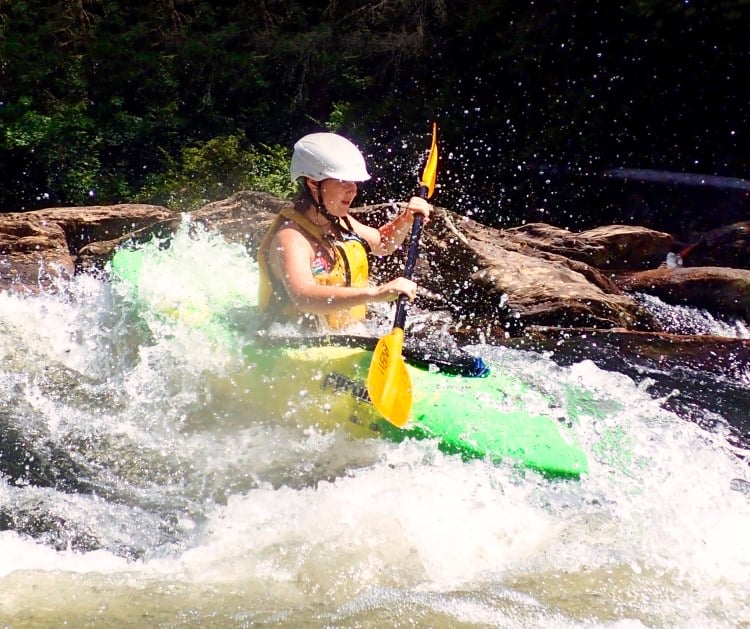camp girl kayaking through whitewater rapid