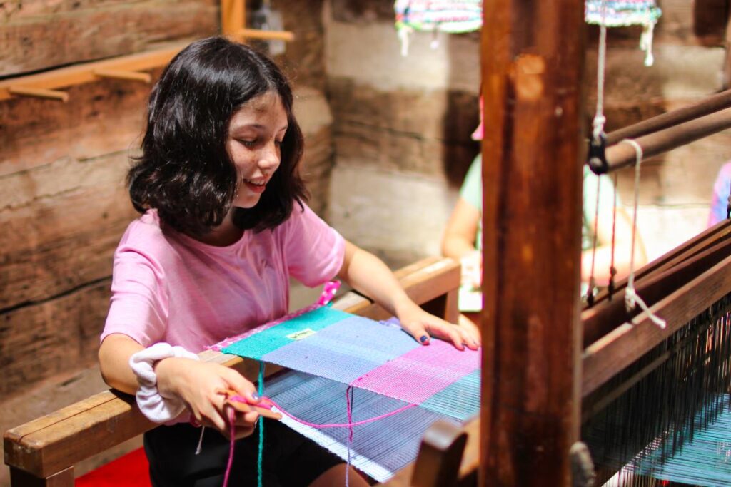 small child weaving on loom