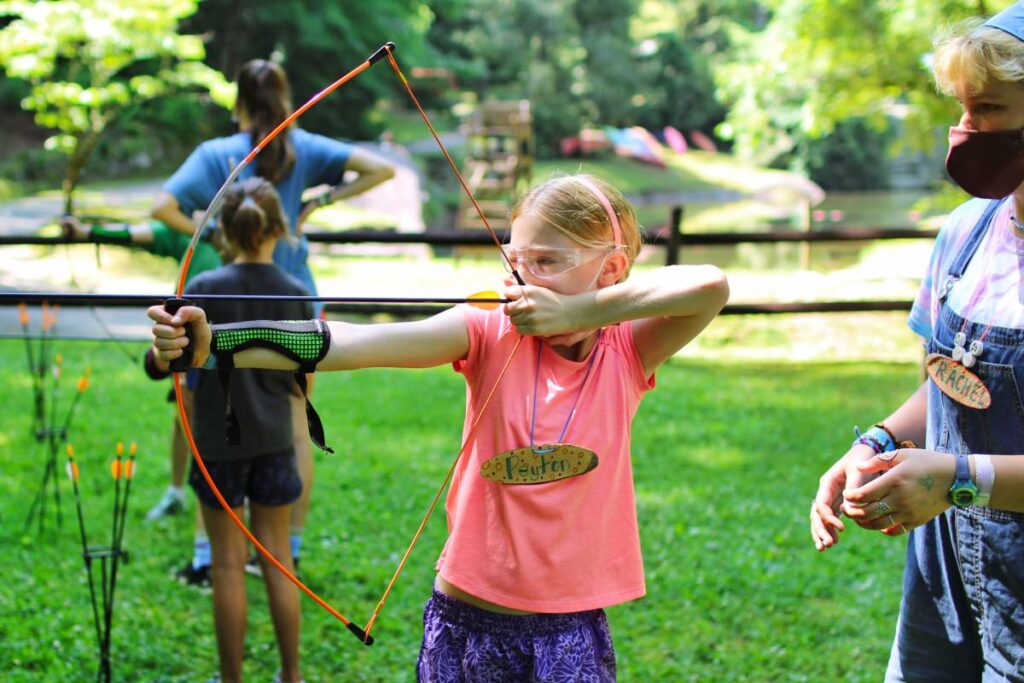 girl learning archery at camp