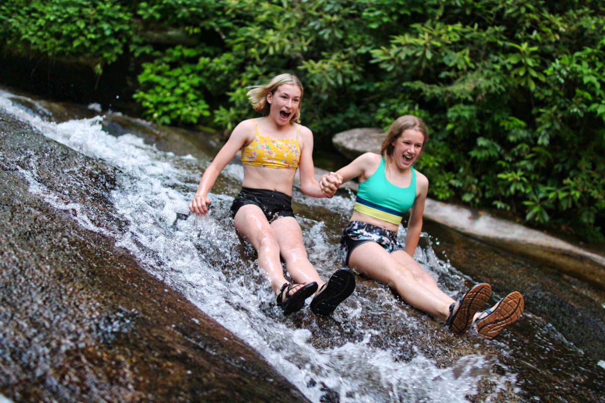 Two teen girls sliding down nc rock