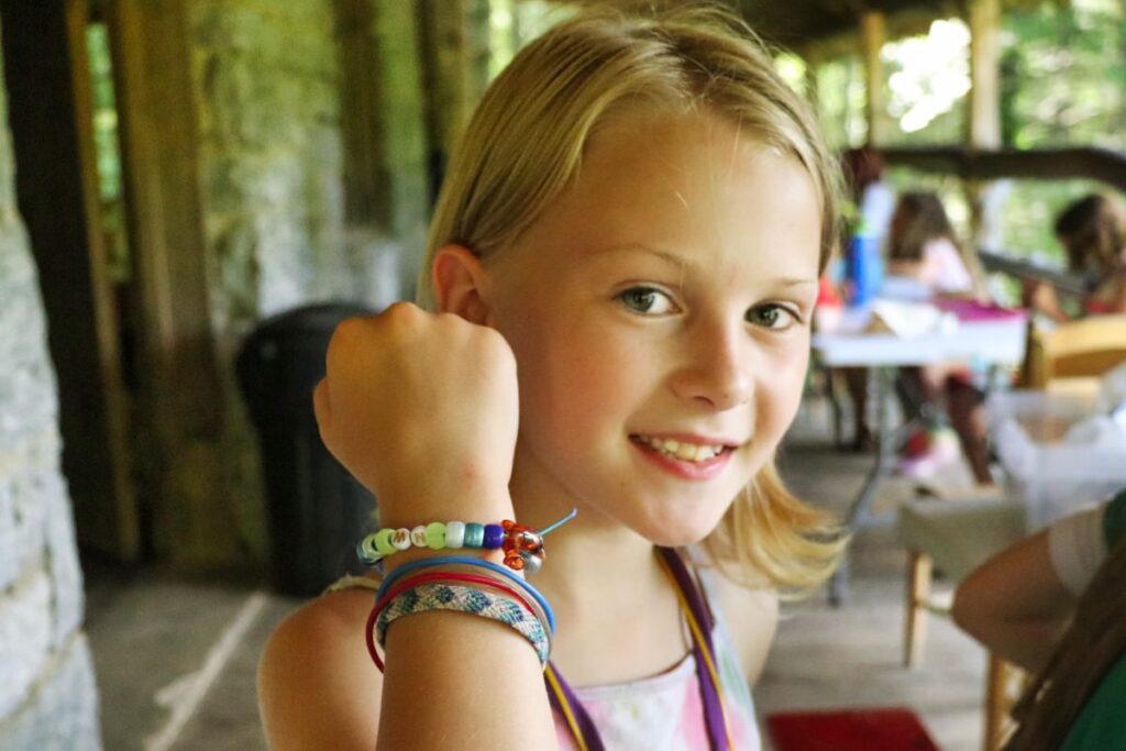 blond child hold up wrist with bracelets
