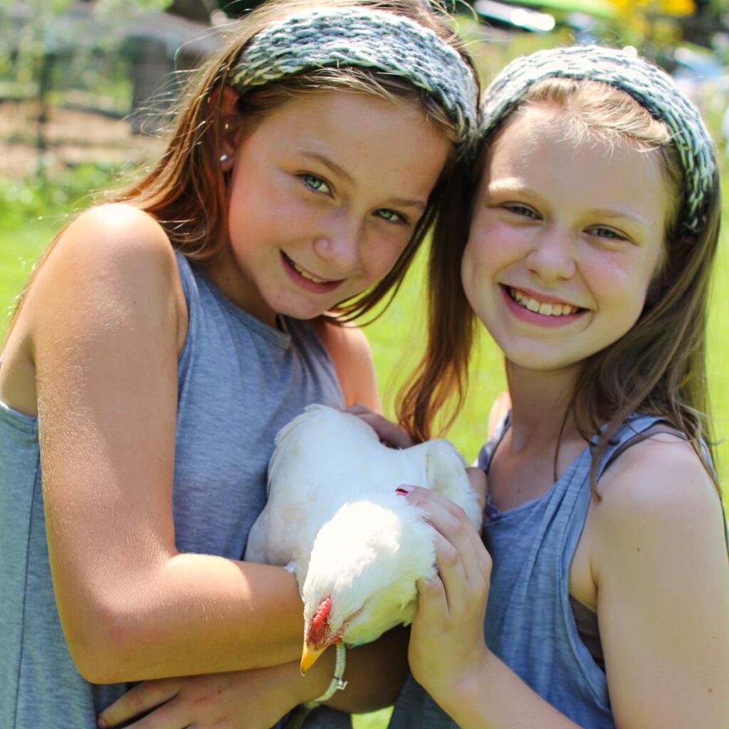 girls holding chicken at camp