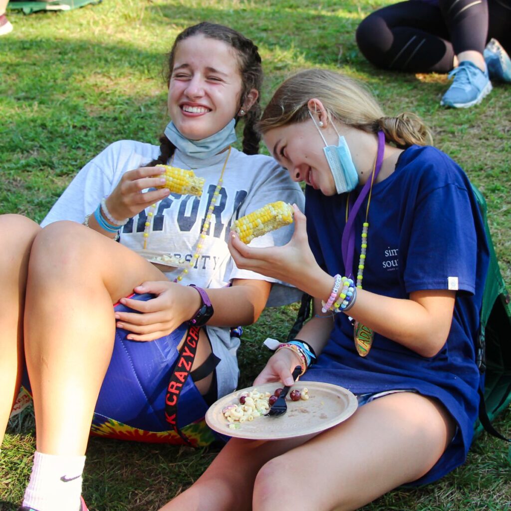 two girls eating picnic dinner at camp